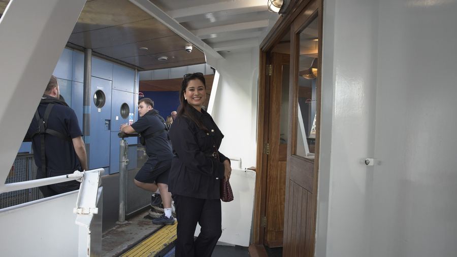A guest in a navy jacket smiles at the camera by the cabin door