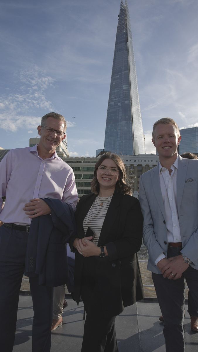 Three guests pose together on deck with the Shard rising behind them
